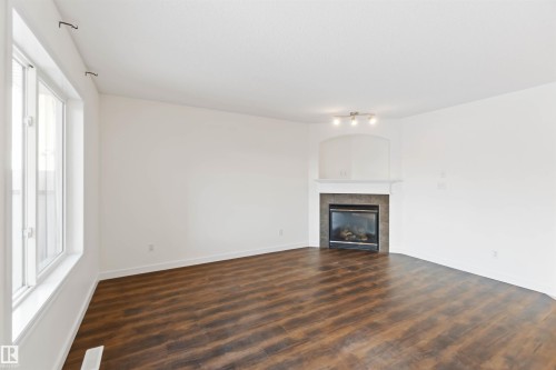 Unfurnished living room with dark wood finished floors and a fireplace - 4507 164A Avenue, Edmonton, AB - Indoor Photo Showing Living Room With Fireplace