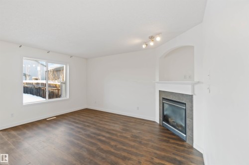 Unfurnished living room featuring dark wood-style flooring and a fireplace - 4507 164A Avenue, Edmonton, AB - Indoor Photo Showing Living Room With Fireplace