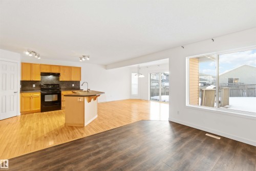Kitchen featuring dark countertops, electric range, open floor plan, light wood-style floors, and decorative backsplash - 4507 164A Avenue, Edmonton, AB - Indoor Photo Showing Kitchen