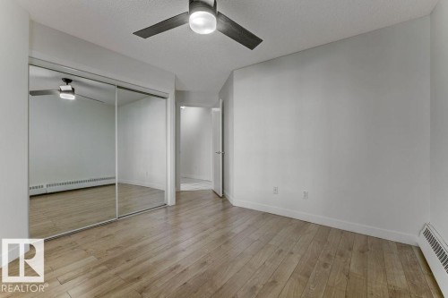 Unfurnished bedroom featuring a baseboard heating unit, ceiling fan, light wood finished floors, a closet, and a textured ceiling - #117 5005 31 Avenue, Edmonton, AB - Indoor Photo Showing Other Room