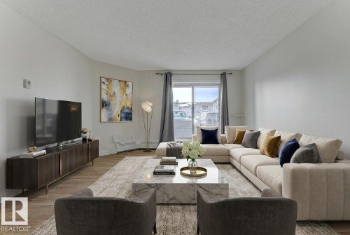 Living area with wood finished floors, a textured ceiling, and baseboard heating - #117 5005 31 Avenue, Edmonton, AB - Indoor Photo Showing Living Room