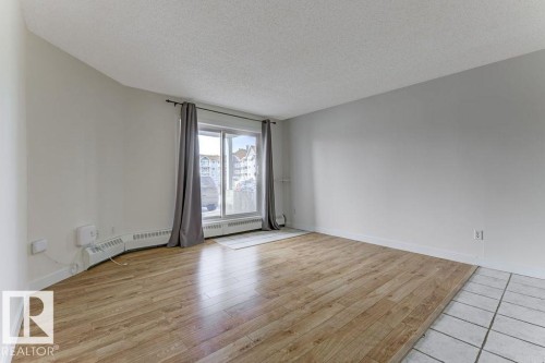 Unfurnished room featuring a textured ceiling, light wood-style floors, and a baseboard heating unit - #117 5005 31 Avenue, Edmonton, AB - Indoor Photo Showing Other Room