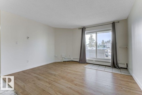 Unfurnished room featuring light wood-type flooring, a textured ceiling, and a baseboard radiator - #117 5005 31 Avenue, Edmonton, AB - Indoor Photo Showing Other Room