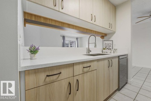 Kitchen with light wood finish cabinets, light tile patterned flooring, ceiling fan, dishwasher, and light stone counters - #117 5005 31 Avenue, Edmonton, AB - Indoor Photo Showing Kitchen