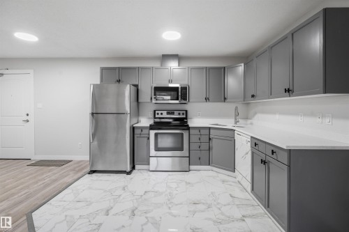 Kitchen featuring gray cabinetry, stainless steel appliances, and light countertops - 115 2098 Blackmud Creek Drive, Edmonton, AB - Indoor Photo Showing Kitchen With Stainless Steel Kitchen