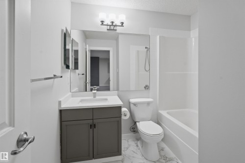 Bathroom with vanity, tub / shower combination, and a textured ceiling - 115 2098 Blackmud Creek Drive, Edmonton, AB - Indoor Photo Showing Bathroom