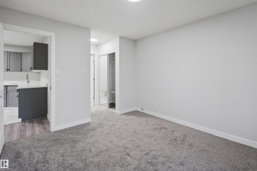 Unfurnished bedroom featuring carpet, freestanding refrigerator, and ensuite bath - 115 2098 Blackmud Creek Drive, Edmonton, AB - Indoor Photo Showing Other Room