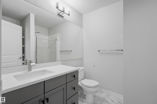 Full bath featuring vanity, a stall shower, light marble finish floors, and a textured ceiling - 115 2098 Blackmud Creek Drive, Edmonton, AB - Indoor Photo Showing Bathroom