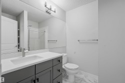 Full bathroom featuring a shower stall, vanity, a textured ceiling, and light marble finish flooring - 