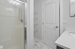 Full bath featuring vanity, a stall shower, light marble finish floors, and a textured ceiling - 