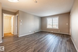 Unfurnished room featuring a textured ceiling, wood finished floors, and a baseboard radiator - 