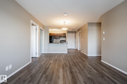 Unfurnished living room featuring dark wood-style floors and baseboards - 433 3315 James Mowatt Trail, Edmonton, AB - Indoor Photo Showing Other Room