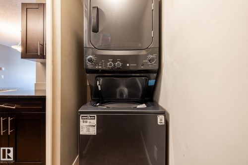 Laundry area featuring stacked washer and dryer - 433 3315 James Mowatt Trail, Edmonton, AB - Indoor Photo Showing Laundry Room