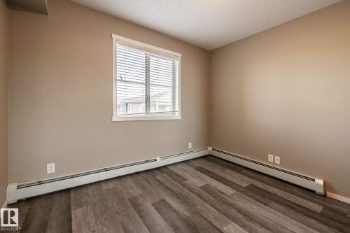 Unfurnished room featuring wood finished floors, a textured ceiling, and a baseboard radiator - 433 3315 James Mowatt Trail, Edmonton, AB - Indoor Photo Showing Other Room