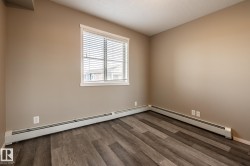 Unfurnished room featuring wood finished floors, a textured ceiling, and a baseboard radiator - 