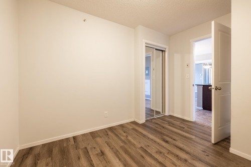 Spare room featuring a textured ceiling and dark wood-style floors - 433 3315 James Mowatt Trail, Edmonton, AB - Indoor Photo Showing Other Room
