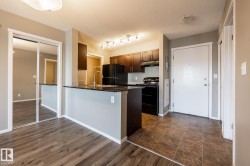 Kitchen featuring black appliances, dark wood-style flooring, a textured ceiling, a peninsula, and dark stone countertops - 