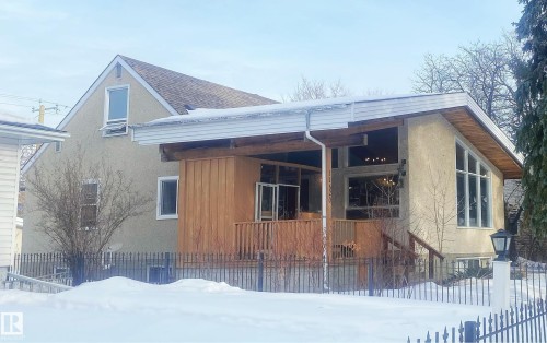 Snow covered property with stucco siding, a porch, and roof with shingles - 11520 78 Avenue Nw, Edmonton, AB - Outdoor