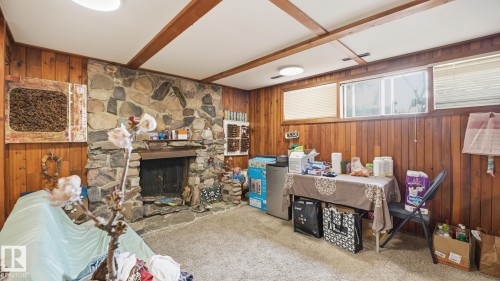 Carpeted living area with wood walls, a fireplace, and beam ceiling - 11520 78 Avenue Nw, Edmonton, AB - Indoor Photo Showing Other Room With Fireplace