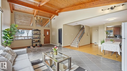Living room with a high wood beamed ceiling, light tile patterned floors, and suspended lighting - 11520 78 Avenue Nw, Edmonton, AB - Indoor