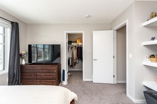 Bedroom featuring light colored carpet, a walk in closet, and a textured ceiling - 4008 Allan Crescent, Edmonton, AB - Indoor Photo Showing Bedroom