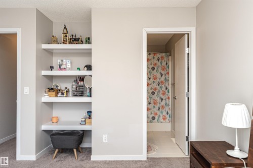 Bedroom with built in study area, light carpet, ensuite bathroom, and a textured ceiling - 4008 Allan Crescent, Edmonton, AB - Indoor