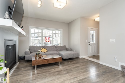 Living area featuring a glass covered fireplace and light wood-style floors - 4008 Allan Crescent, Edmonton, AB - Indoor Photo Showing Living Room