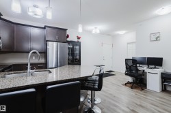 Kitchen featuring light stone countertops, decorative light fixtures, stainless steel appliances, dark wood finish cabinets, and a kitchen bar - 