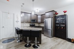 Kitchen with stainless steel appliances, a peninsula, a kitchen bar, pendant lighting, and light wood-style floors - 