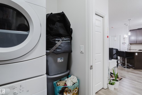 Laundry area featuring stacked washer and dryer, light wood-style floors, and a textured ceiling - 415 2203 44 Avenue, Edmonton, AB - Indoor Photo Showing Kitchen