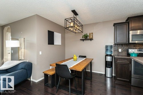 Dining area featuring dark wood-style flooring, a textured ceiling, a chandelier, and arched walkways - 6649 Cardinal Road Sw, Edmonton, AB - Indoor