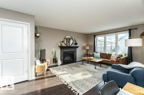 Living room with wood-type flooring, a fireplace, and a textured ceiling - 6649 Cardinal Road Sw, Edmonton, AB - Indoor Photo Showing Living Room With Fireplace
