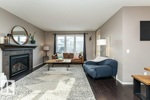 Living room with dark wood finished floors, a tiled fireplace, and a textured ceiling - 6649 Cardinal Road Sw, Edmonton, AB - Indoor Photo Showing Living Room With Fireplace