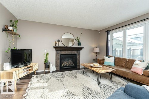 Living room featuring wood finished floors, a fireplace, and a textured ceiling - 6649 Cardinal Road Sw, Edmonton, AB - Indoor Photo Showing Living Room With Fireplace