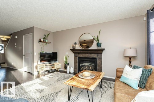 Living room featuring a fireplace, hardwood / wood-style floors, and a textured ceiling - 6649 Cardinal Road Sw, Edmonton, AB - Indoor Photo Showing Living Room With Fireplace