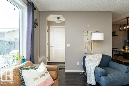 Living area with dark wood-style flooring, a textured ceiling, and arched walkways - 6649 Cardinal Road Sw, Edmonton, AB - Indoor