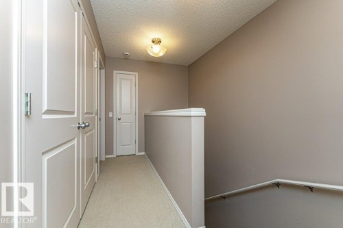 Corridor with an upstairs landing, light carpet, and a textured ceiling - 6649 Cardinal Road Sw, Edmonton, AB - Indoor Photo Showing Other Room
