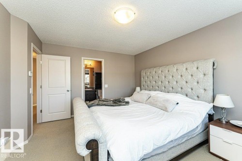 Bedroom with a textured ceiling, carpet floors, and ensuite bathroom - 6649 Cardinal Road Sw, Edmonton, AB - Indoor Photo Showing Bedroom