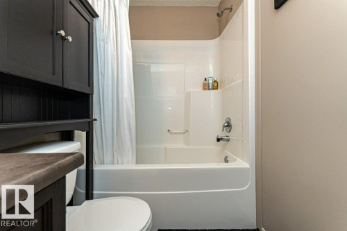 Bathroom with toilet and shower / bath combo with shower curtain - 6649 Cardinal Road Sw, Edmonton, AB - Indoor Photo Showing Bathroom