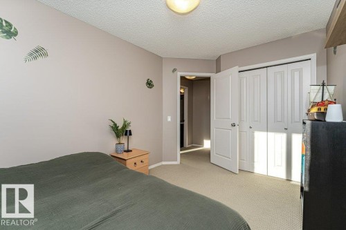 Bedroom with light colored carpet, a textured ceiling, and a closet - 6649 Cardinal Road Sw, Edmonton, AB - Indoor Photo Showing Bedroom