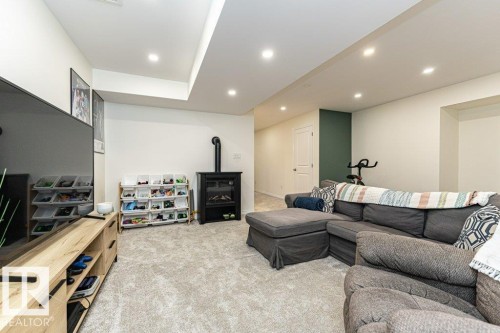 Living area with light carpet, a wood stove, and recessed lighting - 6649 Cardinal Road Sw, Edmonton, AB - Indoor With Fireplace