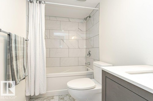 Full bath featuring shower / bathtub combination with curtain, vanity, and light marble finish flooring - 6649 Cardinal Road Sw, Edmonton, AB - Indoor Photo Showing Bathroom