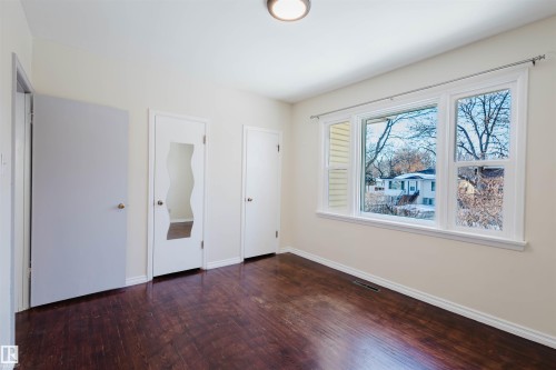 Unfurnished bedroom with dark wood-style floors and baseboards - 10511 80 Street, Edmonton, AB 