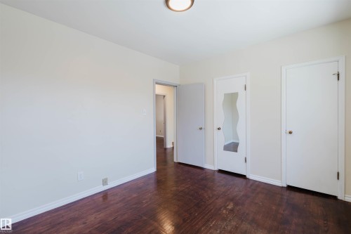 Unfurnished bedroom with dark wood-type flooring and baseboards - 10511 80 Street, Edmonton, AB 