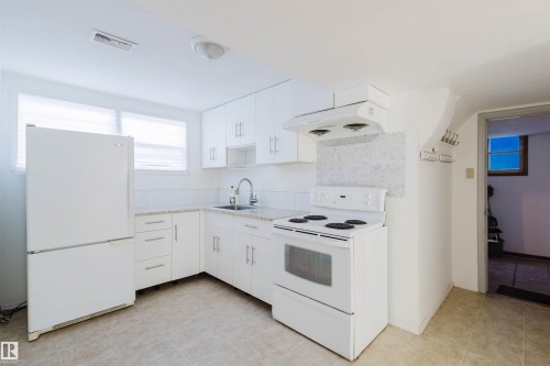 Kitchen featuring white appliances, white cabinets, extractor fan, and light tile patterned flooring - 10511 80 Street, Edmonton, AB 