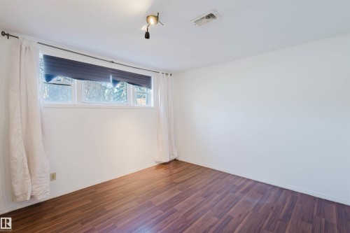 Unfurnished room featuring wood finished floors and baseboards - 10511 80 Street, Edmonton, AB 