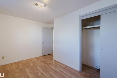Unfurnished bedroom with light wood finished floors and a closet - 10511 80 Street, Edmonton, AB 
