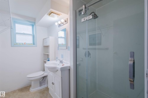 Bathroom with a shower stall, vanity, light tile patterned flooring, decorative backsplash, and tile walls - 10511 80 Street, Edmonton, AB 