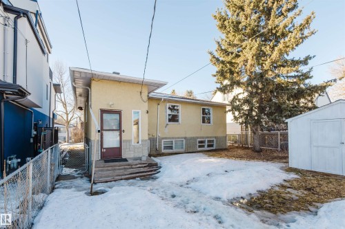 Snow covered property featuring stucco siding, a storage unit, and a gate - 10511 80 Street, Edmonton, AB 