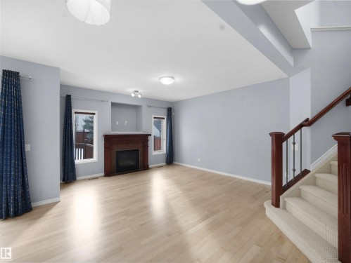 Unfurnished living room with light wood finished floors and a tiled fireplace - 6115 11 Avenue, Edmonton, AB - Indoor Photo Showing Living Room With Fireplace